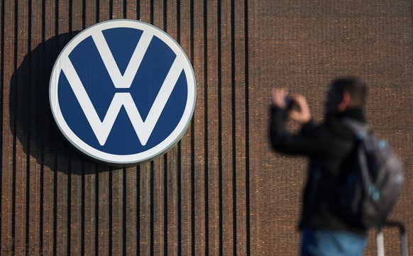 epa11947108 A person takes pictures of the logo of German car maker Volkswagen (VW) on a wall at the company&#039;s plant in Wolfsburg, Germany, 07 March 2025. The company will hold the annual press c ...