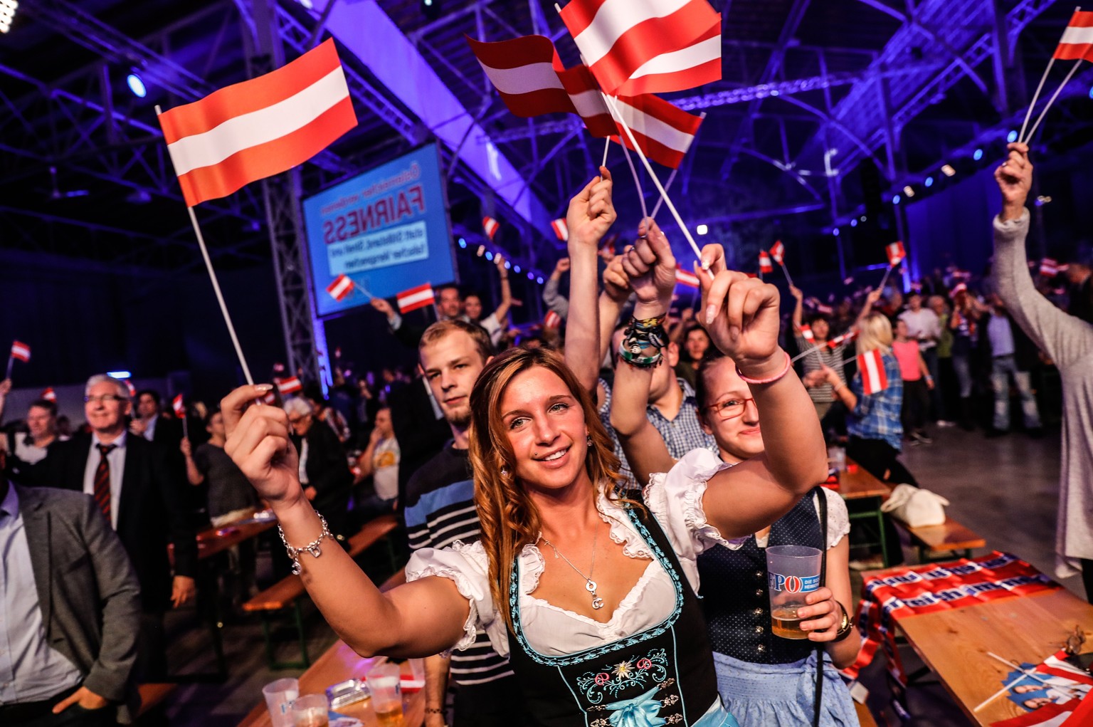 epa06267811 Supporters of the leader of the right-wing Austrian Freedom Party (FPOe) Heinz-Christian Strache (not pictured) waves small Austrian national flags as they watch a projection of the Austri ...