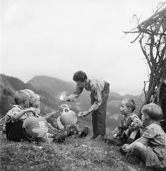 Ein Junge zĂŒndet an einer 1.-Augustfeier 1946 in Gadmen, Kanton Bern, den Kleinen die Lichter ihrer Lampions an.
