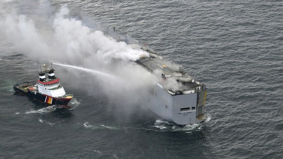 A boat hoses the smoke from a fire which broke out on a freight ship in the North Sea, about 27 kilometers (17 miles) north of the Dutch island of Ameland, Wednesday, July 26, 2023. A fire on the frei ...