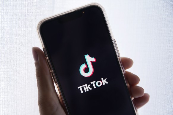 epa10635388 In this photo illustration a person holds up a cell phone with the TikTok logo displayed in Los Angeles, California, USA, 17 May 2023. Govenor Greg Gianforte of Montana signed a measure th ...