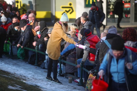 epa09028343 Members of the Food Not Bombs distribute food and clothes to needy residents in Krakow, southern Poland, 21 February 2021, amid the ongoing pandemic of the COVID-19 disease caused by the S ...