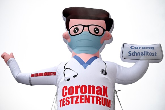 epa09708619 An inflatable airdancer doll points out a test station for coronavirus rapid tests, in Duesseldorf, Germany,25 January 2022. Certain groups of people in Germany will soon be prioritized fo ...