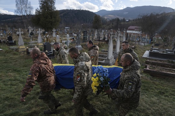 Ukrainian servicemen carry the coffin of their comrade Vasyl Boichuk who was killed in Mykolayiv in March 2022, during his funeral ceremony at the cemetery in Iltsi village, Ukraine, Tuesday, Dec. 26, ...