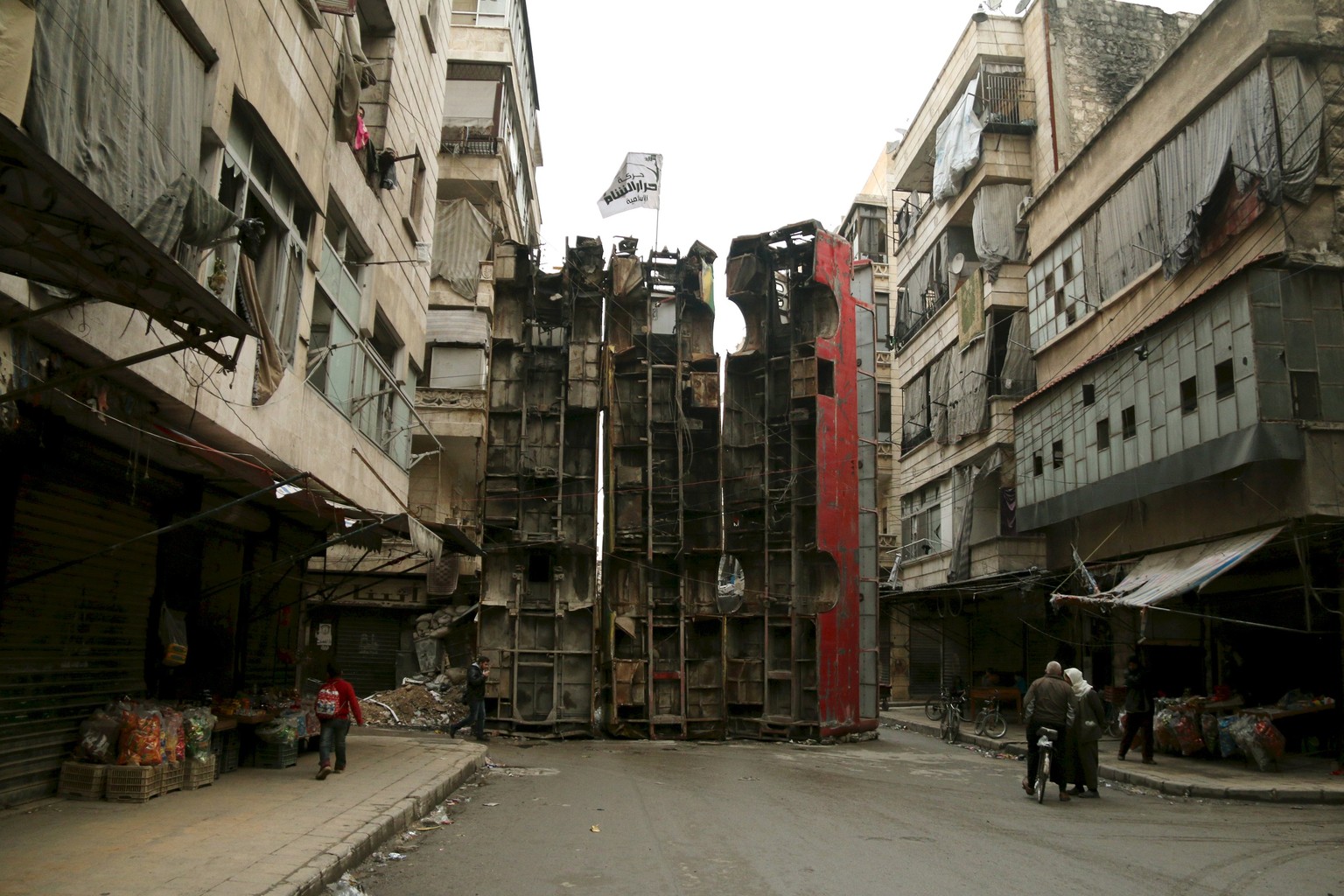 Civilians walk near upright buses barricading a street, which serve as protection from snipers loyal to Syria&#039;s President Bashar al-Assad, in Aleppo&#039;s rebel-controlled Bustan al-Qasr neighbo ...