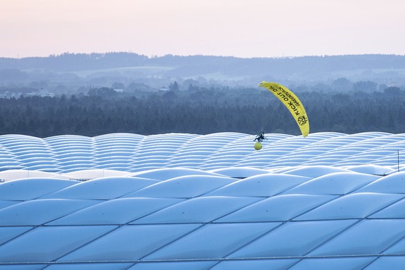 A man in a Greenpeace paraglider flies into the stadium prior to the Euro 2020 soccer championship group F match between France and Germany at the Allianz Arena stadium in Munich, Tuesday, June 15, 20 ...