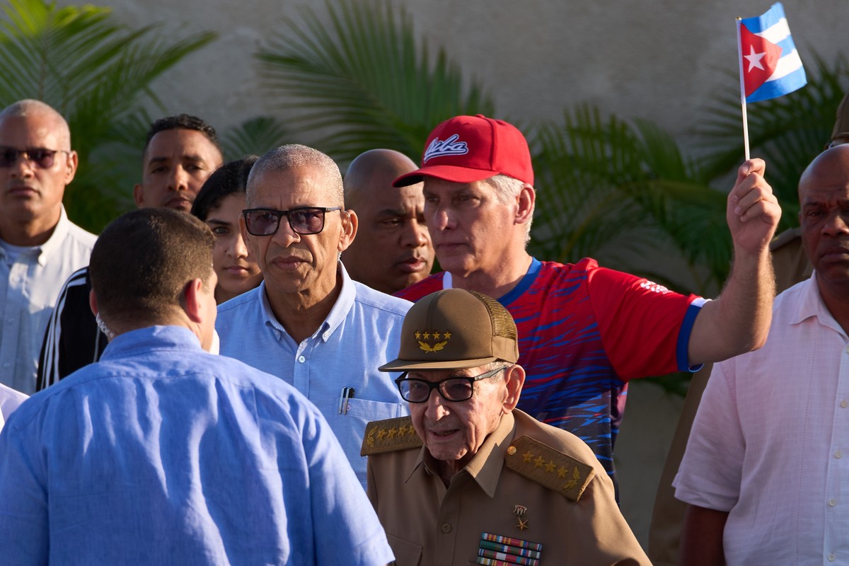 Former President Raul Castro, center, and Cuban President Miguel Díaz-Canel, behind with flag, arrive for a gathering marking International Workers' Day at Jose Marti Anti-Imperialist Square in H ...