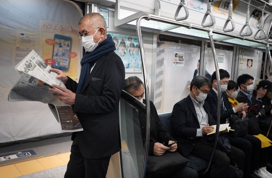 epa08326196 Commuters wearing masks ride in a subway in Tokyo, Japan, 27 March 2020. Tokyo Governor Koike asked for people to stay home on the 28-29 March weekend amid a sharp increase in the number o ...