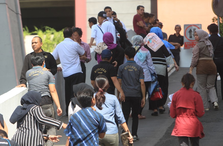 epa06466702 Employees walk outside a building after an earthquake caused office workers to flee swaying buildings, in Jakarta, Indonesia, 23 January 2018. Shakes were felt in Jakarta after a 6.0 magni ...