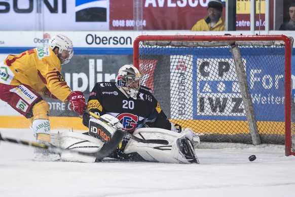 L’attaquant de Langnau Aaron Gagnon, gauche, lutte pour le puck avec le gardien Fribourgeois Reto Berra, droite, lors de la rencontre du championnat suisse de hockey sur glace de National League entre ...