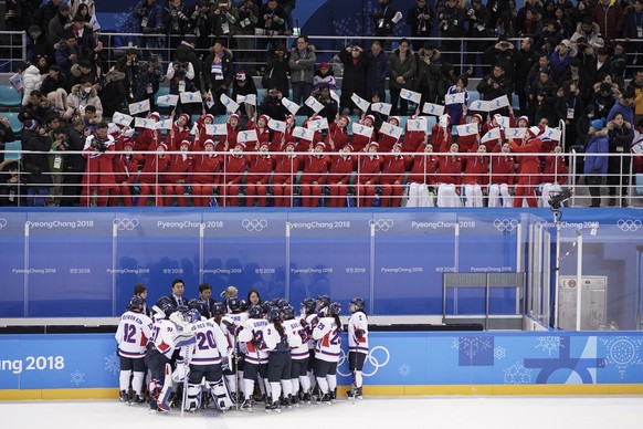 North Korea supporters, top, wave the Korean unification flag as players of combined Koreas gather at the end of a women&#039;s hockey game against Switzerland at the 2018 Winter Olympics in Gangneung ...