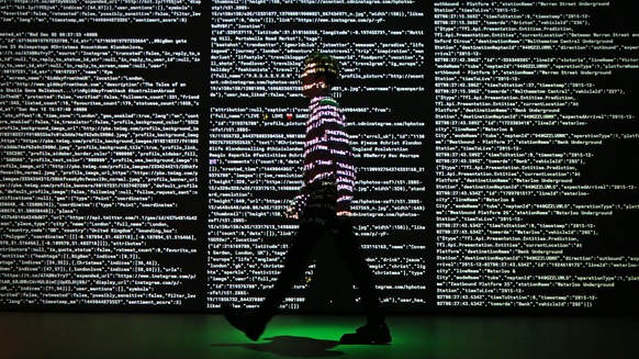 LONDON, ENGLAND - DECEMBER 02: A staff member passes a projection of live data feeds from (L-R) Twitter, Instagram and Transport for London at the Big Bang Data exhibition at Somerset House on Decembe ...