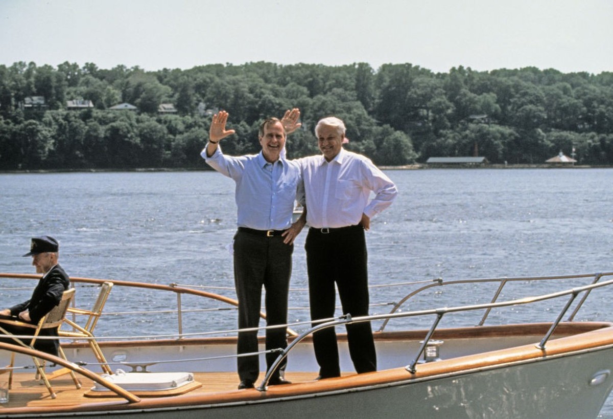 View of US President George HW Bush (center left) and Russian Federation President Boris Yeltsin (1931 - 2007) (right) wave from a boat during a cruise on the Severn River, Maryland, June 17, 1992. Th ...