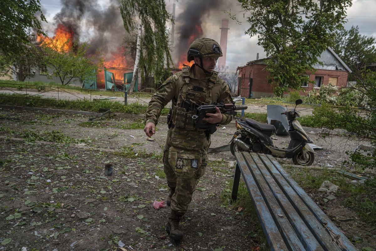 A police officer runs in front on burning house destroyed by a Russian airstrike in Vovchansk, Ukraine, on Saturday, May 11, 2024. (AP Photo/Evgeniy Maloletka)