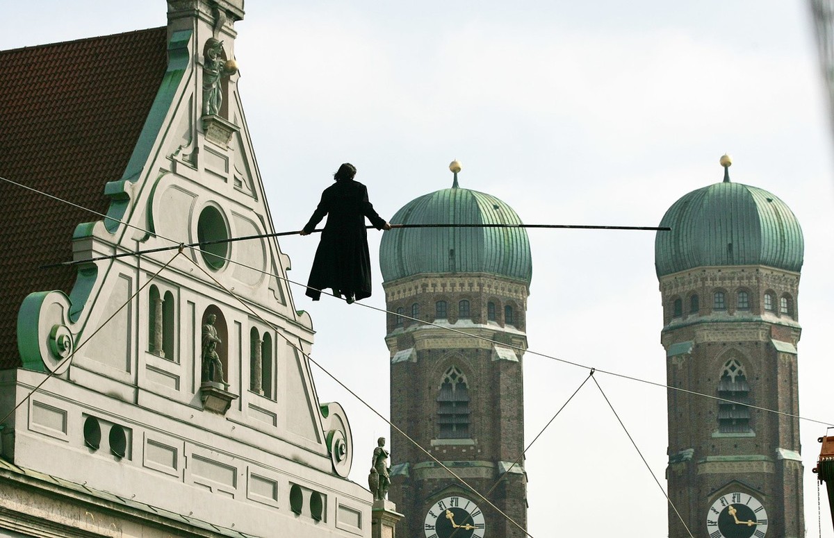 Hoch ueber der Fussgaengerzone geht der Schweizer Artist Freddy Nock am Donnerstag, 31. Maerz 2005, vor den Tuermen der Frauenkirche in Muenchen mit wehendem Mantel ueber ein Hochseil. In 30 Meter Hoe ...