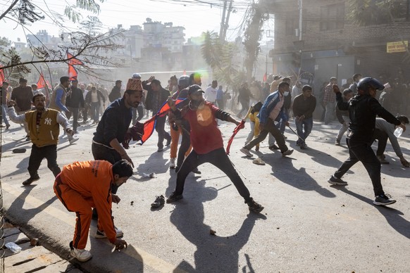 epa10990652 Nepalese pro-monarchy supporters throw rocks during clashes with the police during a rally in Kathmandu, Nepal, 23 November 2023. Nepalese businessman Durga Prasai organized the pro-monarc ...