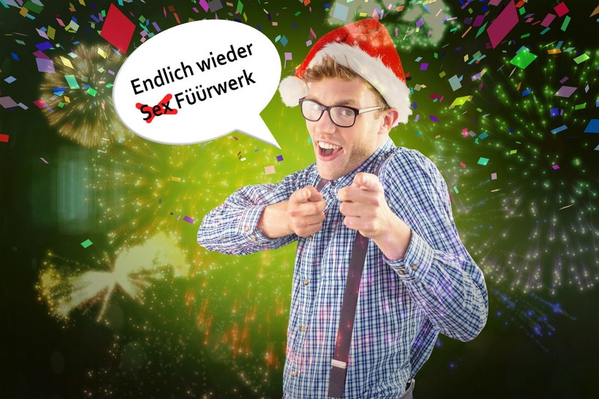 Geeky hipster wearing santa hat against colourful fireworks exploding on black background