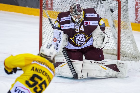 Le defenseur bernois Calle Andersson, gauche, a la lutte pour le puck avec le gardien genevois Gauthier Descloux, droite, lors du match du championnat suisse de hockey sur glace de National League LNA ...