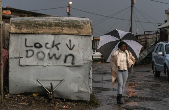 epa08478835 A woman walks along a flooded road amidst a storm in the Masiphumelele informal settlement in Cape Town, South Africa, 11 June 2020. Cape Town is the epicenter of the Coronavirus pandemic  ...