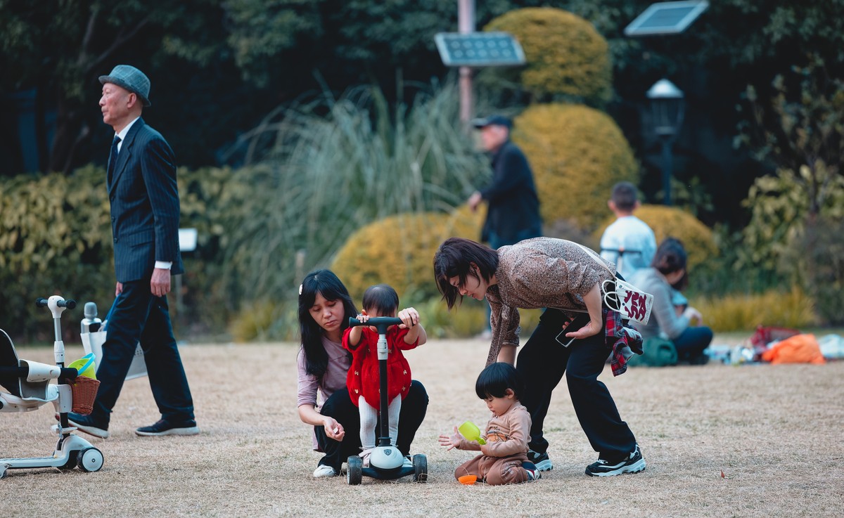 epa11934229 People play with their children on the grass in a park in Shanghai, China, 02 March 2025. EPA/ALEX PLAVEVSKI