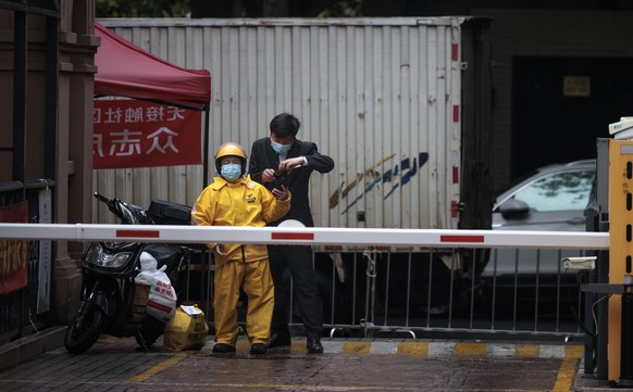 epa09941885 A delivery worker (L) shows his health QR code on the entrance to residential compound under quarantine, amid the ongoing Covid-19 lockdown in Shanghai, China, 12 May 2022. Shanghai city r ...