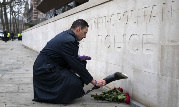 epa05865238 A member of the public lays flowers outside New Scotland Yard in central London, Britain 23 March 2017. Scotland Yard said on 23 March 2017 that police have made seven arrests in raids car ...