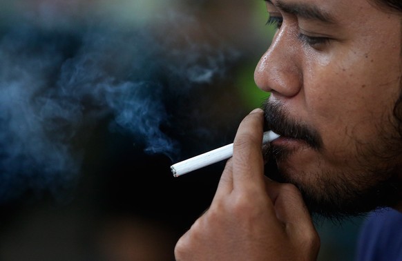 epa10379026 A man smokes a cigarette at a street in Jakarta, Indonesia, 27 December 2022. Indonesian President Joko Widodo has issued Presidential Decree of the Republic of Indonesia concerning the 20 ...
