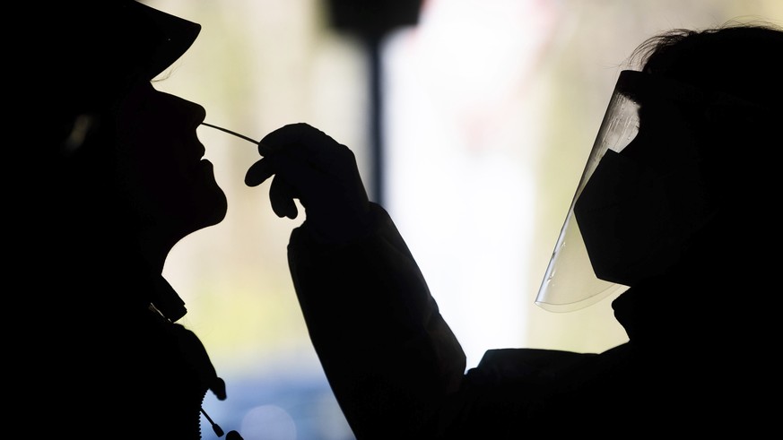 Helpers test a woman at a test center for the novel corona virus using a rapid test in Hannover, Germany, Friday, April 16, 2021. The Robert Koch Institute (RKI) continues to report an increase in new ...