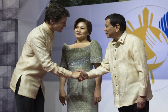 Canadian Prime Minister Justin Trudeau shakes hands with Philippine President Rodrigo Duterte, right, and Honeylet Avancena as he arrives at the ASEAN Summit dinner in Manila, Philippines, Sunday, Nov ...