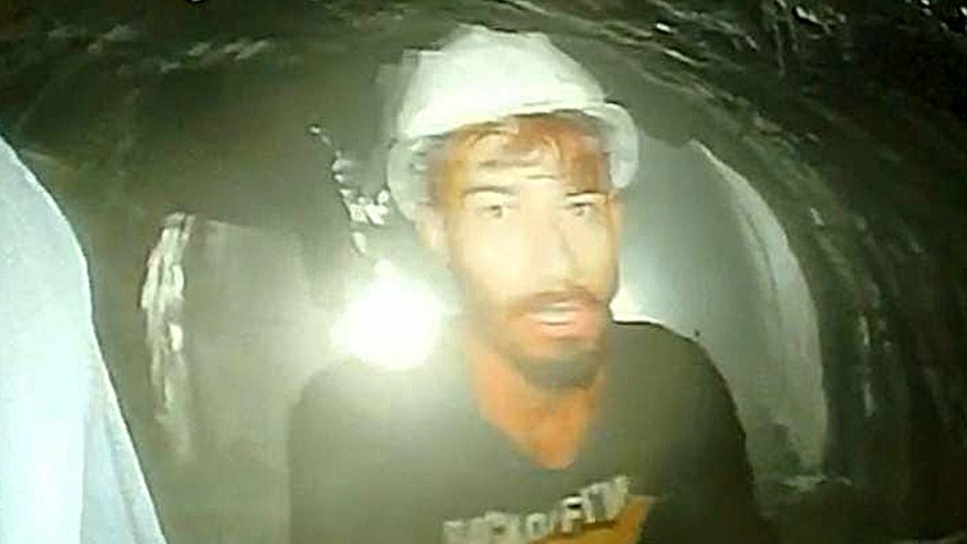 epa10987151 A handout photo made available by the Information Department, Uttarkashi Government of India shows a trapped laborer in a tunnel standing in front of a camera sent through a pipe by rescue ...