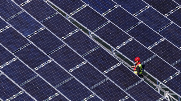 epa07906927 A worker assembles floating barges with solar panels on the Lac des Toules, an alpine reservoir lake, in Bourg-Saint-Pierre, Switzerland, 08 October 2019 (issued 09 October 2019) Upon comp ...