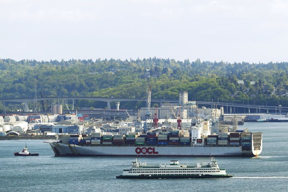 A Washington state ferry passes a Hong-Kong based Orient Overseas Container Line cargo container ship entering the Port of Seattle, Thursday, April 30, 2020, as seen from the city&#039;s Kerry Park. ( ...