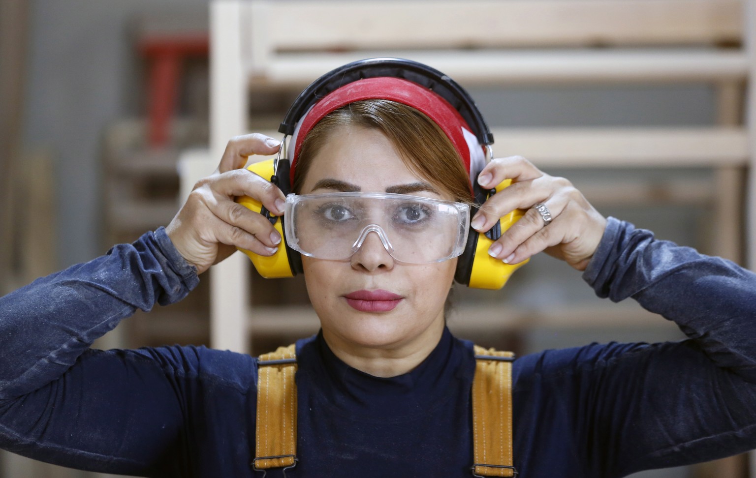 epa10604566 Iranian woman carpenter Sahar Biglari adjusts ear protectors while working at her workshop in Tehran, Iran, 02 May 2023. Biglari, 41, says she left her job as a math and physics teacher to ...