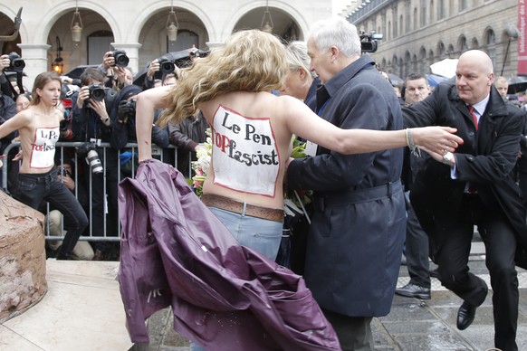 Femen activists with &quot;Le Pen Top Fascist painted on their bodies appear as France’s far-right National Front president Marine Le Pen places a wreath at Joan of Arc Statue during its annual May Da ...