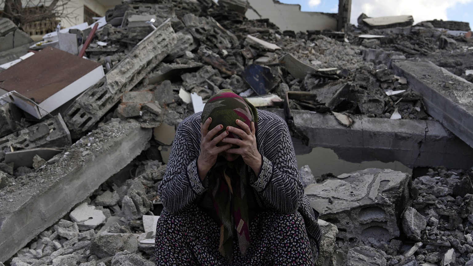 A woman sits on the rubble as emergency rescue teams search for people under the remains of destroyed buildings in Nurdagi town on the outskirts of Osmaniye city southern Turkey, Tuesday, Feb. 7, 2023 ...