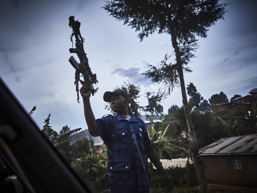 epa07580036 A Congolese police officer reacts to disperse angry crowds who had interrupted and blockaded the quadruple burial of Ebola victims; Kasereka Sahanane, Kathingu Kipura, Kasereka Kipura and  ...