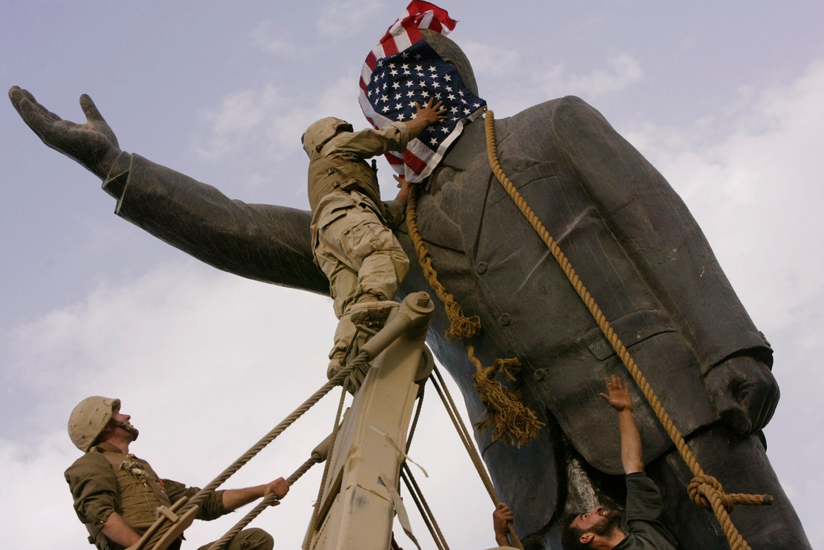 FILE - Cpl. Edward Chin of the 3rd Battalion, 4th Marines Regiment, covers the face of a statue of Saddam Hussein with an American flag before toppling the statue in downtown Baghdad, Iraq, on April 9 ...