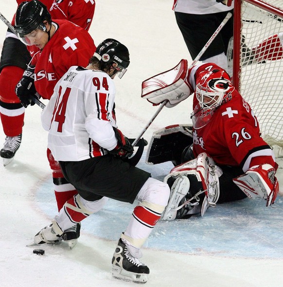 Switzerland's Martin Gerber (R) stop Canada's Ryan Smith (C) in front of the net during the Men's Preliminary Round game between Canada and Switzerland at the Turin 2006 Winter Olympic  ...