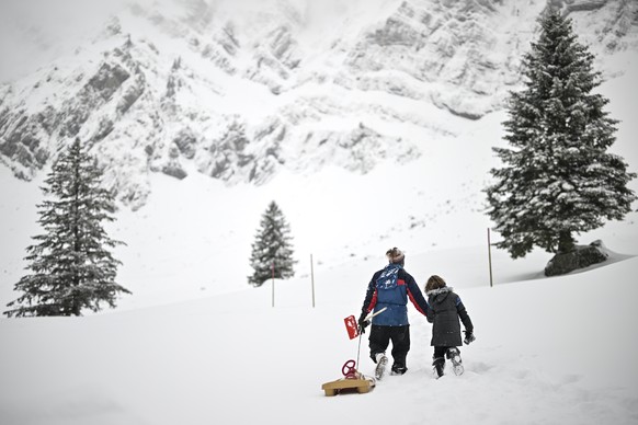 Vater und Sohn mit Bob im Neuschnee, aufgenommen am Montag, 27. Maerz 2023, auf der Schwaegalp in Urnaesch. (KEYSTONE/Gian Ehrenzeller)