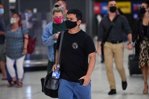 epa08925529 People are seen in the baggage collection area after arriving on Virgin Australia flight VA318 from Brisbane at Tullamarine Airport in Melbourne, Australia, 08 January 2021. A cleaner at a ...