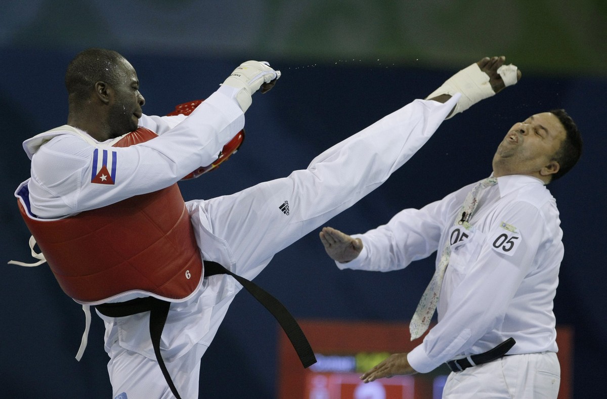 Cuba's Angel Valodia Matos, left, kicks match referee Sweden's Chakir Chelbat in the face during a bronze medal match against Kazakhstan's Arman Chilmanov in the men's taekwondo +8 ...