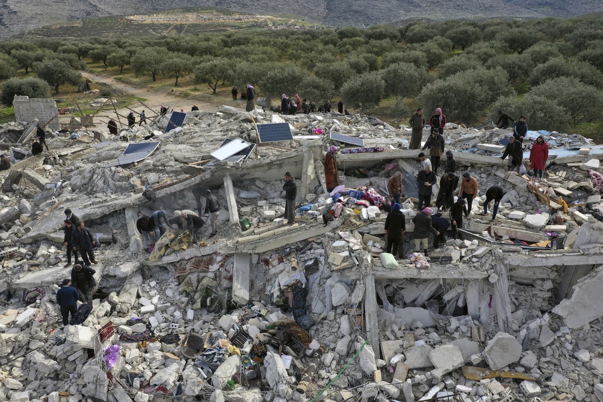 Civil defense workers and residents search through the rubble of collapsed buildings in the town of Harem near the Turkish border, Idlib province, Syria, Monday, Feb. 6, 2023. A powerful earthquake ha ...