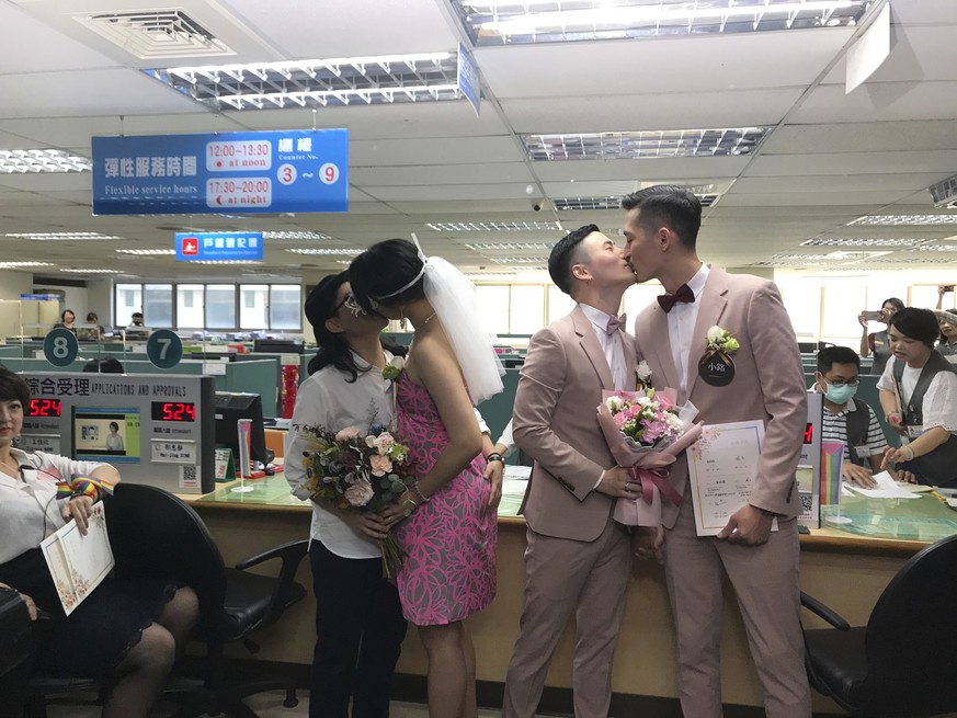 Two same-sex couple seal their legal marriages with a kiss at the registration office in Xingyi District in Taipei, Taiwan, Friday, May 24, 2019. Hundreds of same-sex couples in Taiwan are rushing to  ...