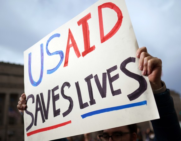 epa11873497 A protester holds a placard outside the US Agency for International Development (USAID) in Washington, DC, USA, 03 February 2025. Staffers at USAID have been instructed via an email to sta ...