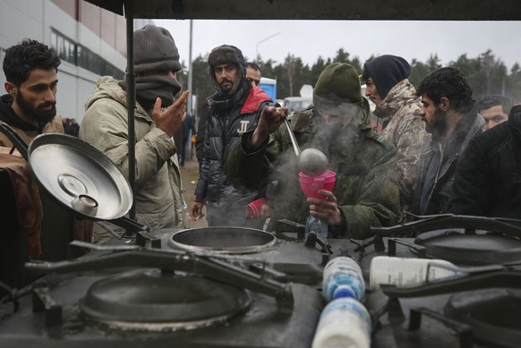 Migrants receive food delivered by Belarusian officials in the logistics center at the checkpoint &quot;Kuznitsa&quot; at the Belarus-Poland border near Grodno, Belarus, on Friday, Nov. 19, 2021. Hund ...