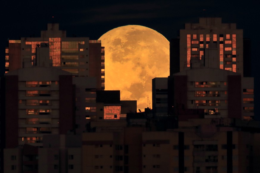 The moon is partially covered by buildings in Brasilia, Brazil, at the start of a total lunar eclipse early Wednesday, May 26, 2021. Wednesday