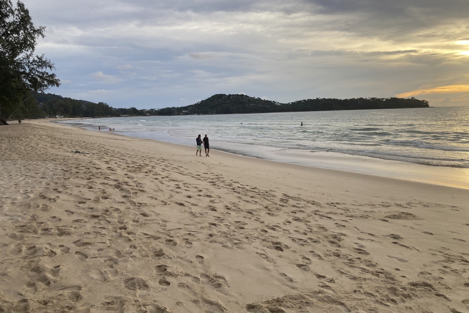 Tourists walk on Bang Tao Beach in Phuket, southern Thailand, Friday, Oct. 22, 2021. Thailand is accelerating plans to reopen the country to foreign tourists, slashing mandatory quarantines beginning  ...