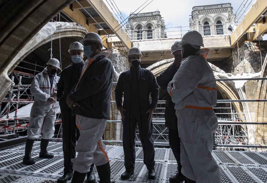 epa09136848 French President Emmanuel Macron (C) , Mayor of Paris Anne Hidalgo (R) and the French Army General Jean-Louis Georgelin (L) tour the scaffolding under the vault at the reconstruction site  ...