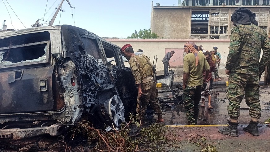 epa09516875 Yemeni soldiers inspect the scene of a car bomb attack which targeted the convoy of government officials in the southern port city of Aden, Yemen, 10 October 2021. At least five people wer ...