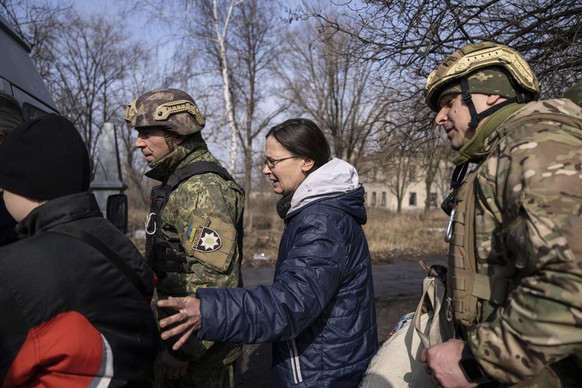 Olga Shulga and her son Myroslav, board a van during an evacuation by Ukrainian police, in Avdiivka, Ukraine, Tuesday, March 7, 2023. For months, authorities have been urging civilians in areas near t ...